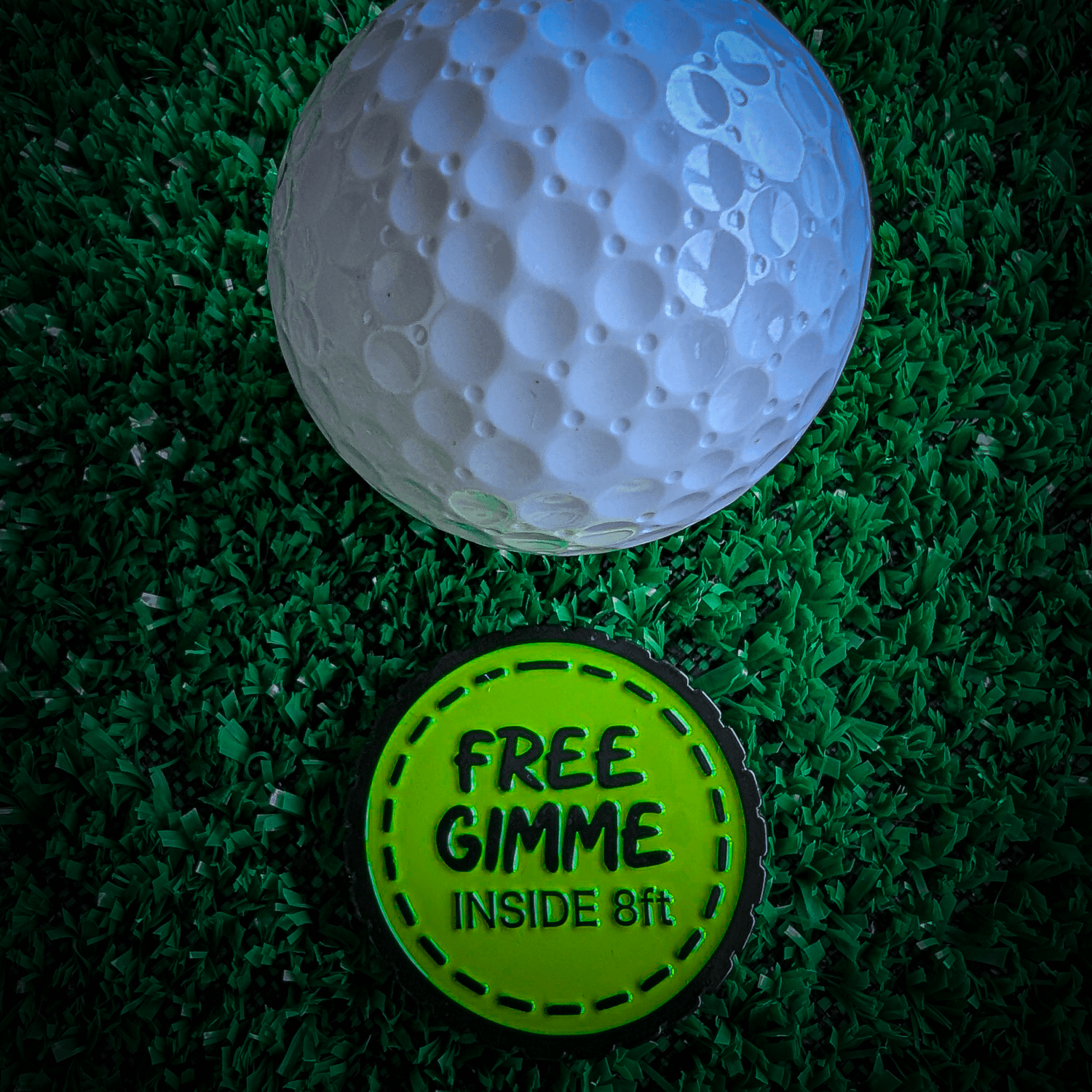 芝生の上でゴルフボールに添えた黄色のFree Gimmeボールマーカー